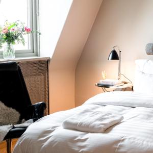 a bedroom with a bed and a chair and a window at The Duxiana Malmö in Malmö
