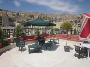 a patio with tables and chairs and an umbrella at Jordan Tower Hotel in Amman