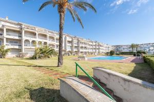 ein Gebäude mit einer Palme und einem Pool in der Unterkunft 1014 Apartamento al lago San Maurici con 1 habitación y piscina in Empuriabrava