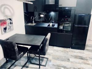 una cocina con electrodomésticos negros y una mesa y sillas negras. en Trendy House 158, en Mátranovák