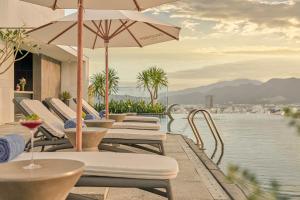 eine Reihe von Stühlen und Tischen mit Sonnenschirmen auf einer Terrasse in der Unterkunft December Hotel in Nha Trang