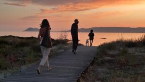 un grupo de personas caminando por un paseo con un perro en Diseño frente al mar en Portosín, en Portosín