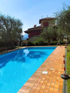 a large blue swimming pool next to a house at ORA Beth's House in Brenzone sul Garda