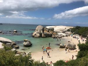 a group of people on a beach with rocks at Seaforth Suite in Simonʼs Town