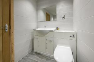 a white bathroom with a toilet and a sink at Woodlands Hall Hotel in Ederyn