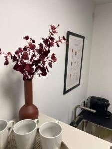 einen Tisch mit drei Tassen und eine Vase mit Blumen in der Unterkunft Oldtown in Trier