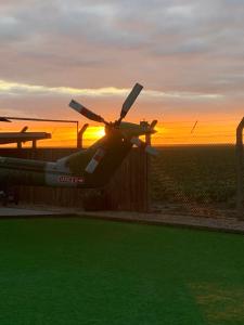 a plane parked next to a fence with the sunset in the background at Helipod in Boston