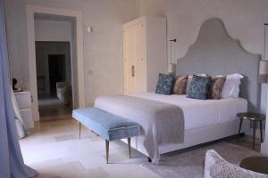 um quarto com uma grande cama branca e um banco azul em Palazzo Maresgallo Suites & SPA em Lecce