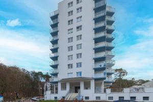 a tall white apartment building with balconies at Beachfront Apartment Campingowa by Renters in Międzyzdroje