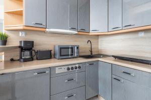 kuchnia z szafkami ze stali nierdzewnej i kuchenką mikrofalową w obiekcie Apartament przy Plaży - Campingowa - Widok na Morze by Noclegi Renters w mieście Międzyzdroje