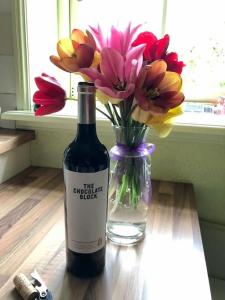 a bottle of wine next to a vase of flowers at Farm apartment, self checkin in Anna Paulowna