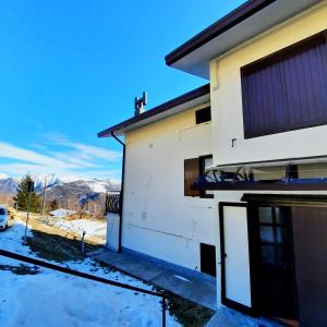 a house with the mountains in the background at Appartamento Monte Muggio - Your Mountain Holiday in Casargo