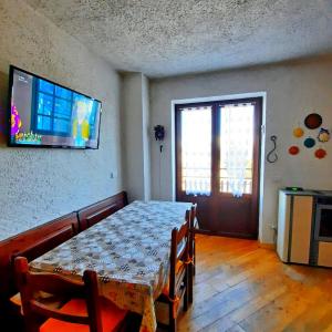 a dining room with a table and a television on the wall at Appartamento Monte Muggio - Your Mountain Holiday in Casargo