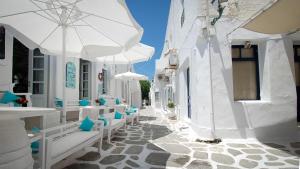 a street with white buildings and chairs and an umbrella at Spiti Georgia in Drios village in Kampos Paros