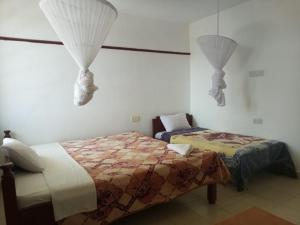 a bedroom with two beds and a window with curtains at Golden Guest House- Miritini in Mombasa
