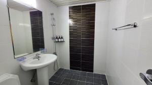 ein Bad mit einem Waschbecken und einer Dusche mit einem Spiegel in der Unterkunft The Oakra Hotel in Jeju-do