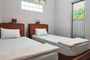 dos camas sentadas una al lado de la otra en una habitación en RedDoorz Syariah Near Tugu Macan Kayu Aro en Kayu Aro
