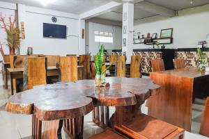 a dining room with wooden tables and chairs at RedDoorz Syariah Near Tugu Macan Kayu Aro in Kayu Aro