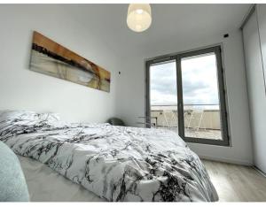 ein weißes Schlafzimmer mit einem Bett und einem Fenster in der Unterkunft Superbe Appartement en Résidence T3,Options Clim et parking, lave-linge in Bagneux