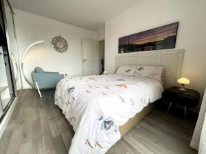 a bedroom with a bed and a clock on the wall at Superbe Appartement en Résidence T3,Options Clim et parking, lave-linge in Bagneux