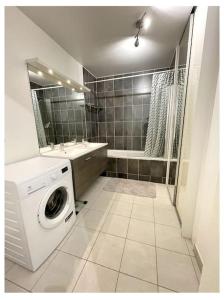 ein Badezimmer mit einer Waschmaschine und einem Waschbecken in der Unterkunft Superbe Appartement en Résidence T3,Options Clim et parking, lave-linge in Bagneux