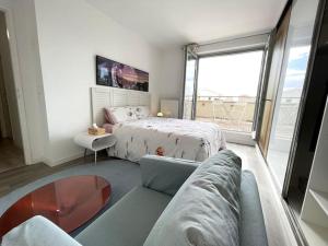 a bedroom with a bed and a couch and a window at Superbe Appartement en Résidence T3,Options Clim et parking, lave-linge in Bagneux