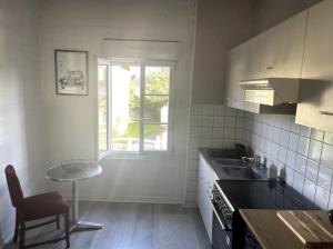 eine Küche mit einem Waschbecken, einem Tisch und einem Fenster in der Unterkunft Appartement au centre de Dinard in Dinard