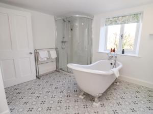 a white bathroom with a tub and a shower at The Old School House in Lower Swell