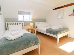 a bedroom with two beds and a window at The Old School House in Lower Swell