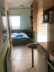 una pequeña cocina con una cama y una mesa en una habitación en Réka Apartmanház, en Bük