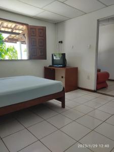 a bedroom with a bed and a tv in it at Chale do Guidon in Imbassai