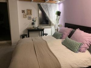 B&B Vintage Room في فوخت: غرفة نوم مع سرير كبير مع وسائد وردية وأخضر