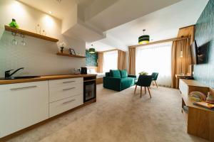 a kitchen with white cabinets and a green couch at Hotel Küküllő - Târnava in Odorheiu Secuiesc