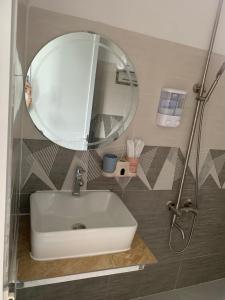 W łazience znajduje się biała umywalka i lustro. w obiekcie Hải Phong hotel w mieście Dien Khanh