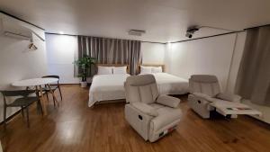 済州市にあるThe Oakra Hotelのベッド、椅子、テーブルが備わるホテルルームです。