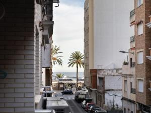 een stadsstraat met gebouwen en palmbomen en de oceaan bij Adorable apartment 60m from the beach WIFI in Puerto de Sagunto