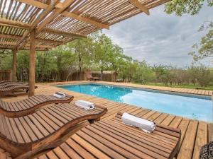una piscina con 2 sillas y una terraza de madera en Langa Langa Tented Safari Camp, en Huntingdon