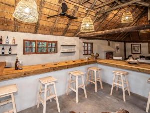 a bar in a restaurant with wooden ceilings and stools at Langa Langa Tented Safari Camp in Huntingdon