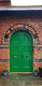 a green door on a brick building with a railway store at The Railway Sleeper in Cullybackey