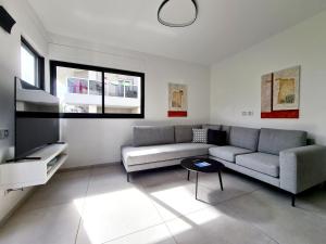 a living room with a couch and a tv at 8 Hulda - By Beach Apartments TLV in Tel Aviv
