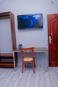 a desk with a chair and a tv on a wall at The VIP Luxury Lounge Hotel in Kisumu