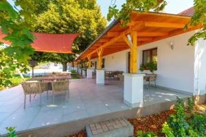 a patio with a table and chairs under a wooden pergola at Barkland Apartman in Tarcal