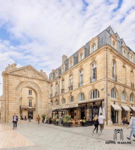 un grand bâtiment avec des personnes qui marchent devant lui dans l'établissement Hôtel Madame, à Bordeaux