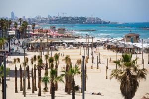 a beach with palm trees and people on the beach at 8 Hulda - By Beach Apartments TLV in Tel Aviv