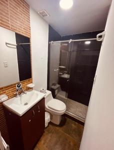 y baño con aseo, lavabo y ducha. en House Studio Hotel, en Bogotá