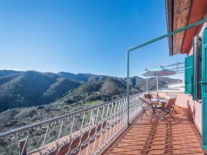 balcón con mesa, sombrilla y montañas en Alpi Apuane Panoramic Apartment, en Carrodano Inferiore
