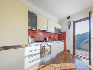 cocina con armarios blancos y ventana grande en Alpi Apuane Panoramic Apartment, en Carrodano Inferiore