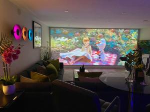 ein Wohnzimmer mit einem großen Bildschirm mit einer Frau darauf in der Unterkunft Sunridge Fishing Lodge with Hot Tub & Giant Cinema in Plymouth