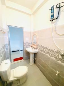 un bagno con un water, un lavandino e uno specchio di Inu Vicky Beach Hotel a Tangalle