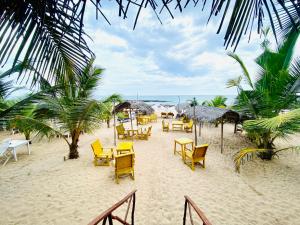 una spiaggia con sedie e tavoli gialli e l'oceano di Inu Vicky Beach Hotel a Tangalle